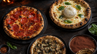 Mehrere Pizzen und Tiramisu auf dunklem Tisch